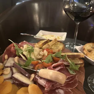 a platter of food and a glass of wine