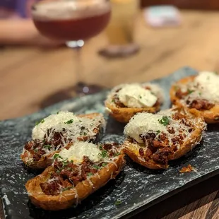a plate of appetizers with a glass of wine in the background