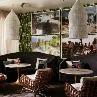 a living room with a black couch and wicker chairs