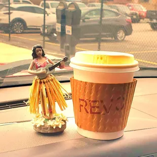 a cup of coffee and a hula girl figurine