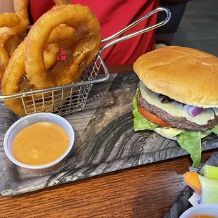 Cheeseburger with onions lettuce and tomatoes, onion rings.