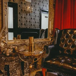 a black leather chair and a gold framed mirror