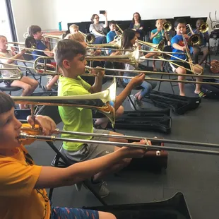 Trombone day during Exploring Instruments Camp. Students are trying instruments out for the first time.