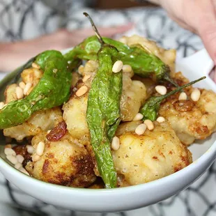 The Crispy Curried Cauliflower is made with blistered shishito peppers, golden raisins, pine nuts, and herbs de provence gastrique.