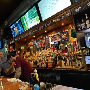 two men at a bar with televisions in the background