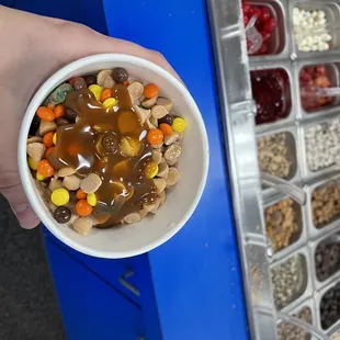 a hand holding a bowl of candy