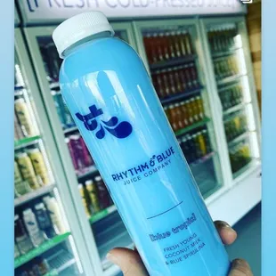 a hand holding a bottle of blue juice