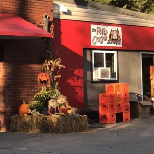 the outside of a restaurant with hay bales and pumpkins