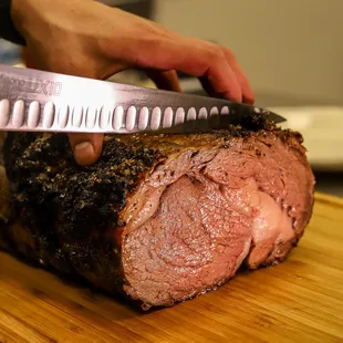 a person holding a knife cutting a roast