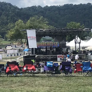a crowd of people sitting in lawn chairs in front of a stage