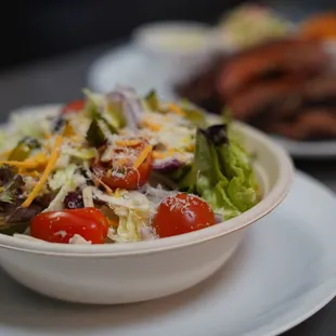 a bowl of salad and a plate of steak