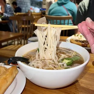 a bowl of noodles with chopsticks