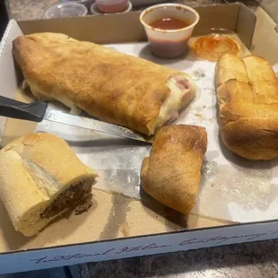 Ham and Cheese Calzone (upper left), garlic bread (far right) and Cheesesteak sub