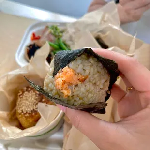 a hand holding a piece of sushi