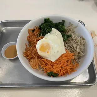 Gluten-free rice bowl w/ carrot, bean sprouts, kale, radish salad and an egg, peanut sauce in the side.