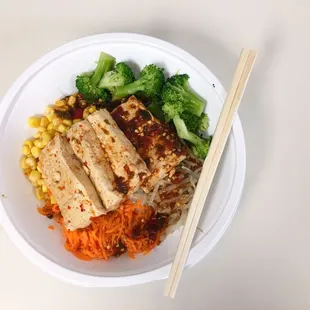 Rice noodles with broccoli, corn, carrots, bean sprouts, spicy tofu, and chili sauce