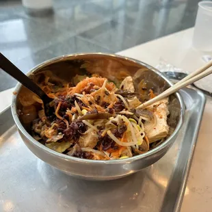 a bowl of food with chopsticks