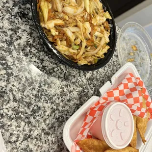 a bowl of noodles and a container of fries