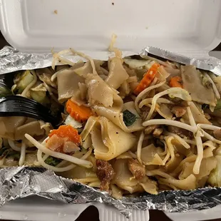 ows a takeout container with noodles and vegetables