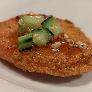 a piece of fried chicken with cucumbers