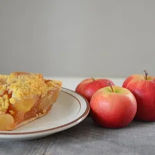a slice of apple pie and three apples