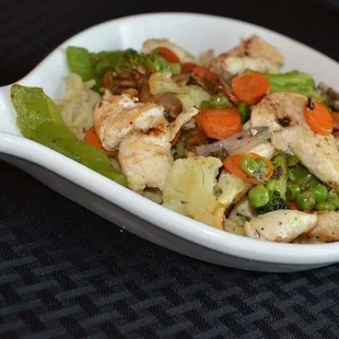 a white spoon filled with chicken and vegetables