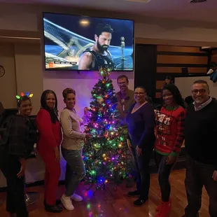 a group of people standing in front of a christmas tree