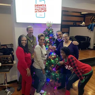 a group of people around a christmas tree