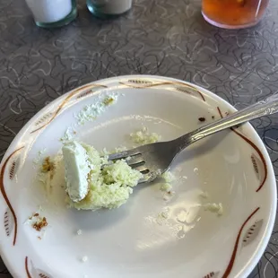 My last bite of fluffy pistachio cake with a light whipped cream frosting . The perfect ending to a tasty meal!