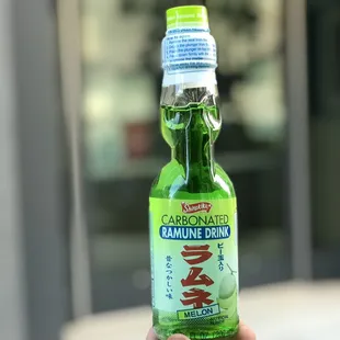 a hand holding a bottle of carcinonate drink