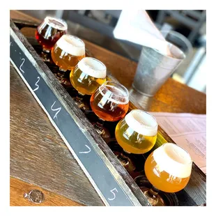 a row of beer glasses on a wooden tray