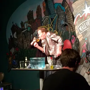 Yes that is a glass with goldfish in it. Yes he swallowed them. And yes he did spit them back up...alive.