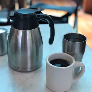 a coffee pot and two cups of coffee