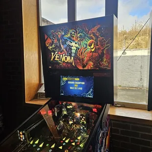 a pinball machine in front of a window