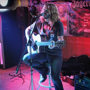 a man sitting on a stool playing a guitar