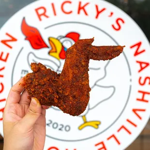 a hand holding a piece of fried chicken