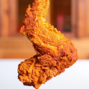 a hand holding a piece of fried chicken