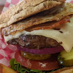 a burger with cheese, tomato, and pickles