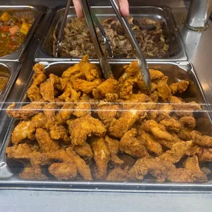 a tray of fried chicken with tongs