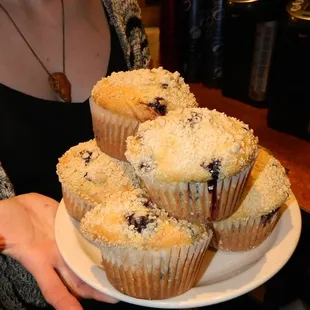 a woman holding a plate of muffins