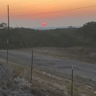 the sun setting behind a fence