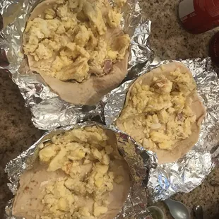 three burritos wrapped in tin foil