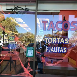 a taco shop window with spider webs