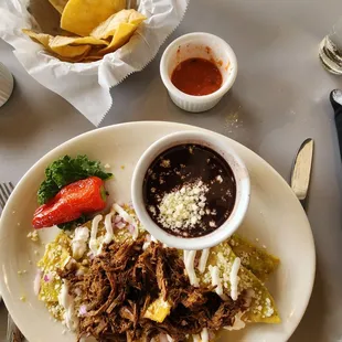 Chilaquiles with green sauce and birria. A side of beans.
