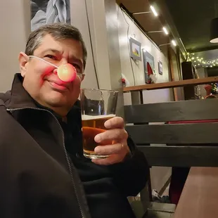 a man with a red nose and a glass of beer