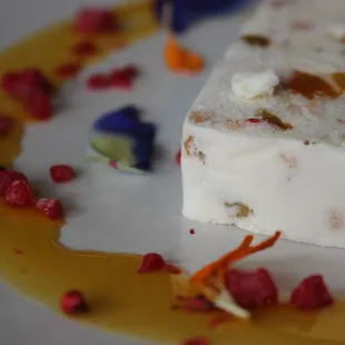 White Chocolate Cassata is italian ice cream cake with walnuts, macadamia nuts, dried fruits, lilikoi sauce, and pink pepper.