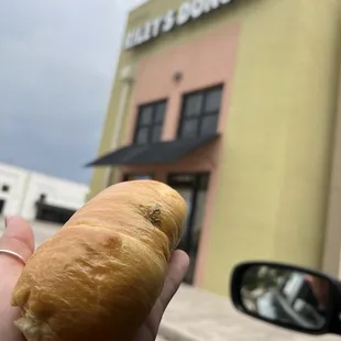 a hand holding a croissant