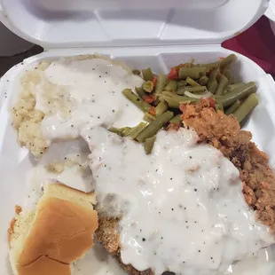 Chicken fried steak with mashed potatoes and green beans and a roll