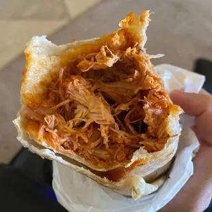 a hand holding a pulled pork sandwich