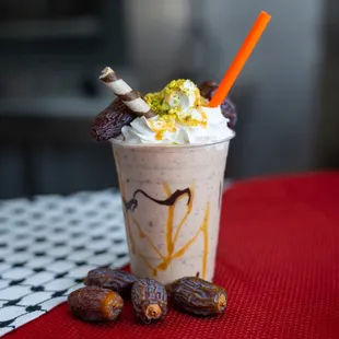 a milkshake topped with whipped cream, dates, and whipped cream